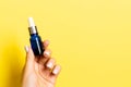 Close up of female hand holding a bottle of cosmetics product at yellow background with copy space Royalty Free Stock Photo