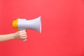 Close up of female hand holding bullhorn public address megaphone, Hot news, announce discounts sale, hurry up, isolated on red Royalty Free Stock Photo