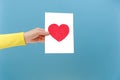 Close up of female hand holding card with heart symbol, posing isolated over plain blue color background wall in studio with copy Royalty Free Stock Photo