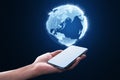 Close up of female hand holding cellphone with glowing globe hologram on blurry blue background. Digital earth and metaverse Royalty Free Stock Photo