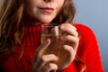 Close up female hand holding cocktail on party. girl in a red sweater holds a glass with champagne,  gray background Royalty Free Stock Photo