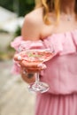 Close up female hand holding cocktail on party. unrecognizable girl in a pink dress holds a glass with champagne Royalty Free Stock Photo