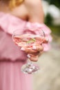 Close up female hand holding cocktail on party. unrecognizable girl in a pink dress holds a glass with champagne Royalty Free Stock Photo