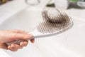 Close-up of female hand holding comb with big clump of lost hair over sink. Concept of baldness and alopecia Royalty Free Stock Photo