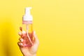 Close up of female hand holding cosmetics spray at yellow background with copy space Royalty Free Stock Photo