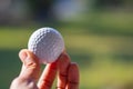 Close-up of Female hand holding golf ball with green background Royalty Free Stock Photo