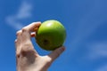 Close-up of female hand holding green apple outdoors. Royalty Free Stock Photo