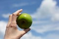 Close-up of female hand holding green apple outdoors. Royalty Free Stock Photo