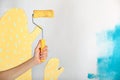 Close up of female hand holding paint yellow roller over white and blue background-repair, construction and building tools concept Royalty Free Stock Photo