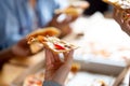 Close up female hand holding piece of pizza, friends together in cafe Royalty Free Stock Photo