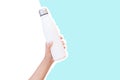 Close-up of female hand holding reusable steel thermo water bottle isolated on background of white and blue color. Royalty Free Stock Photo