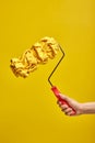 Close up of female hand holds paint roller for wall painting isolated on yellow background Royalty Free Stock Photo