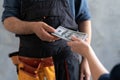 close-up female hand pays for the work of foreman builder repairman with dollar money. construction concept. Focus on Royalty Free Stock Photo