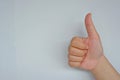 Close-up of female hand showing thumb up sign over on grey background. Side view close up details.