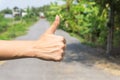 Close up of female hand showing thumbs up sign against on the street. Royalty Free Stock Photo