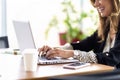 Close-up of female hand typing on computer keyboard while sitting at desk in a modern office and working on the internet