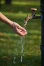 Close-up of female hand under water from an old-style column with drinking water in an autumn park, selective focus Royalty Free Stock Photo