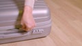 Close up female hand unzip fastener on travel suitcase on wooden floor in room