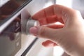 Close up female hand while using the microwave in her kitchen Royalty Free Stock Photo