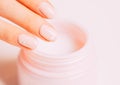 Female hand using moisturizing cream from jar. Royalty Free Stock Photo