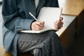 Close-up of a female hand writing on an blank notebook with a pen. Royalty Free Stock Photo