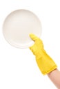 Close up of female hand in yellow protective rubber glove holding clean white plate against white Royalty Free Stock Photo