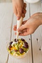 Close up female hands add cream to fruit salad Royalty Free Stock Photo