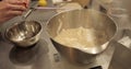 Close-up of female hands breaking an egg and adding it to a bowl