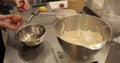 Close-up of female hands breaking an egg and adding it to a bowl