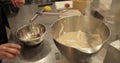 Close-up of female hands breaking an egg and adding it to a bowl