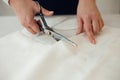 Close-up female hands cuts out a piece of fabric on which a chalk pattern of clothing is marked for tailors