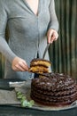 Woman cuts chocolate cake close. Dark tones