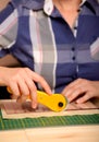 Close-up female hands cutting fabric with patchwork rotating cutter