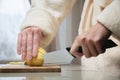 Close-up of female hands cutting peeled potatoes on a wooden cutting board. Home cooking potatoes