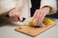 Close-up of female hands cutting peeled potatoes on a wooden cutting board. Home cooking potatoes