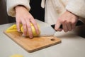 Close-up of female hands cutting peeled potatoes on a wooden cutting board. Home cooking potatoes