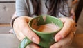 Close up of female hands with a drink mug. A girl in a gray sweater holds a cup of coffee or cocoa in a cafe at the table and Royalty Free Stock Photo