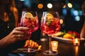 Close up of female hands with glasses of red cocktail in bar, Cropped image of female friends clinking glasses with cocktails at