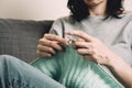 Close up of female hands holding bamboo knitting needles and knitting green woolen sweater. Hobby, relaxation, mental Royalty Free Stock Photo