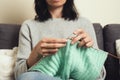 Close up of female hands holding bamboo knitting needles and knitting green woolen sweater. Hobby, relaxation, mental Royalty Free Stock Photo