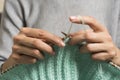 Close up of female hands holding bamboo knitting needles and knitting green woolen sweater. Hobby, relaxation, mental Royalty Free Stock Photo