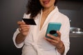 Close-up woman hands holding blank black credit card and smartphone with empty mockup digital screen, transferring money