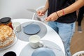 Close-up of female hands holding cake spatula and fork. On the table is a cake, plates and cups. Homemade tea party Royalty Free Stock Photo