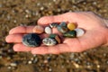 Close-up of female hands holding colorful beach rocks with blurred beach background Royalty Free Stock Photo