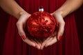 Close up of female hands holding elegant red Christmas tree bauble