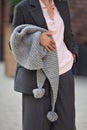 Close up of female hands holding fashion accessory knitted warm scarf, wearing gray wool business suit with jacket and