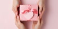 Close up on female hands holding a gift in a pink heart presents for valentine day, birthday, mother\'s day Royalty Free Stock Photo