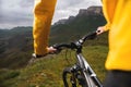 Close-up of female hands holding handlebars of mountain bike outdoors on green grass background