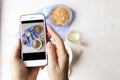 Close up of female hands holding mobile phone taking a picture of granola cereals, milk yogurt and trail mix vegetarian dieting br