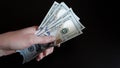 Close-up of female hands holding a pack of one hundred dollar bills.The concept of paying for goods and services, getting paid,